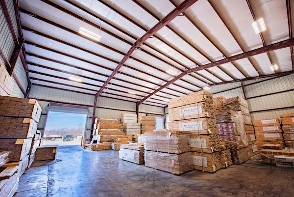 Interior of a commercial metal warehouse stocked with lumber and building materials.
