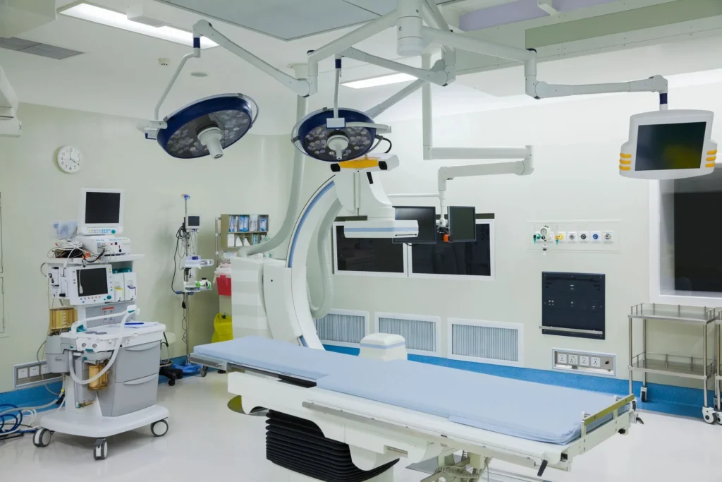 Modern hospital operating room with surgical lights, imaging equipment, and patient bed.