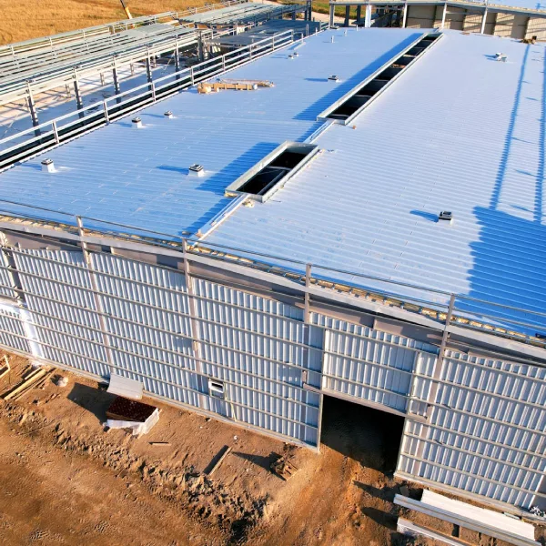 Aerial view of a newly constructed metal commercial building with a standing-seam roof and rooftop openings.